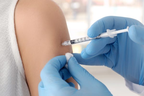 notícia: A vacina da gripe está disponível enquanto durarem os estoques. #Pratodosverem: na foto, uma vacina sendo aplicada. Cores na imagem: azul, branco e preto. 